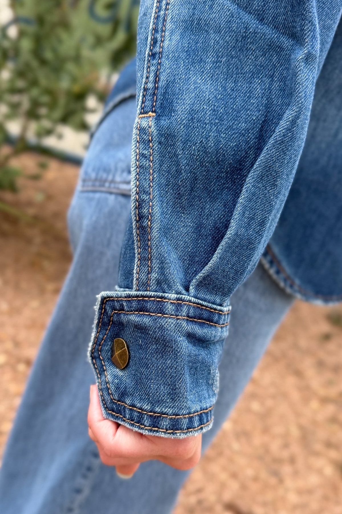 cuff details women’s studded denim shirt jacket in medium wash with antique gold stud details, western-inspired seams and front patch pockets at Cotton & Cashmere in Blanco, Texas.