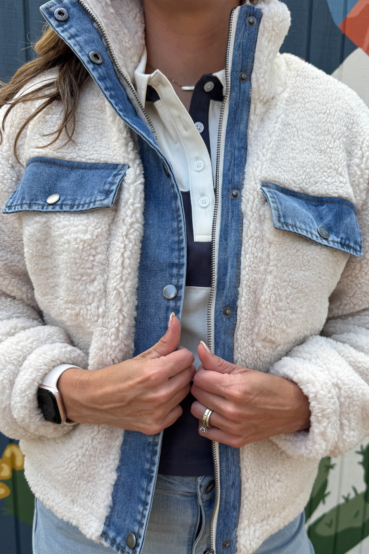 Cozy meets cool in this teddy bear jacket with denim trim. The soft, plush fabric keeps you warm and comfortable, while the cotton jersey lining adds an extra layer of softness. With snap-button chest pockets and a zip front, it’s both practical and stylish — an effortless layering piece for everyday wear.