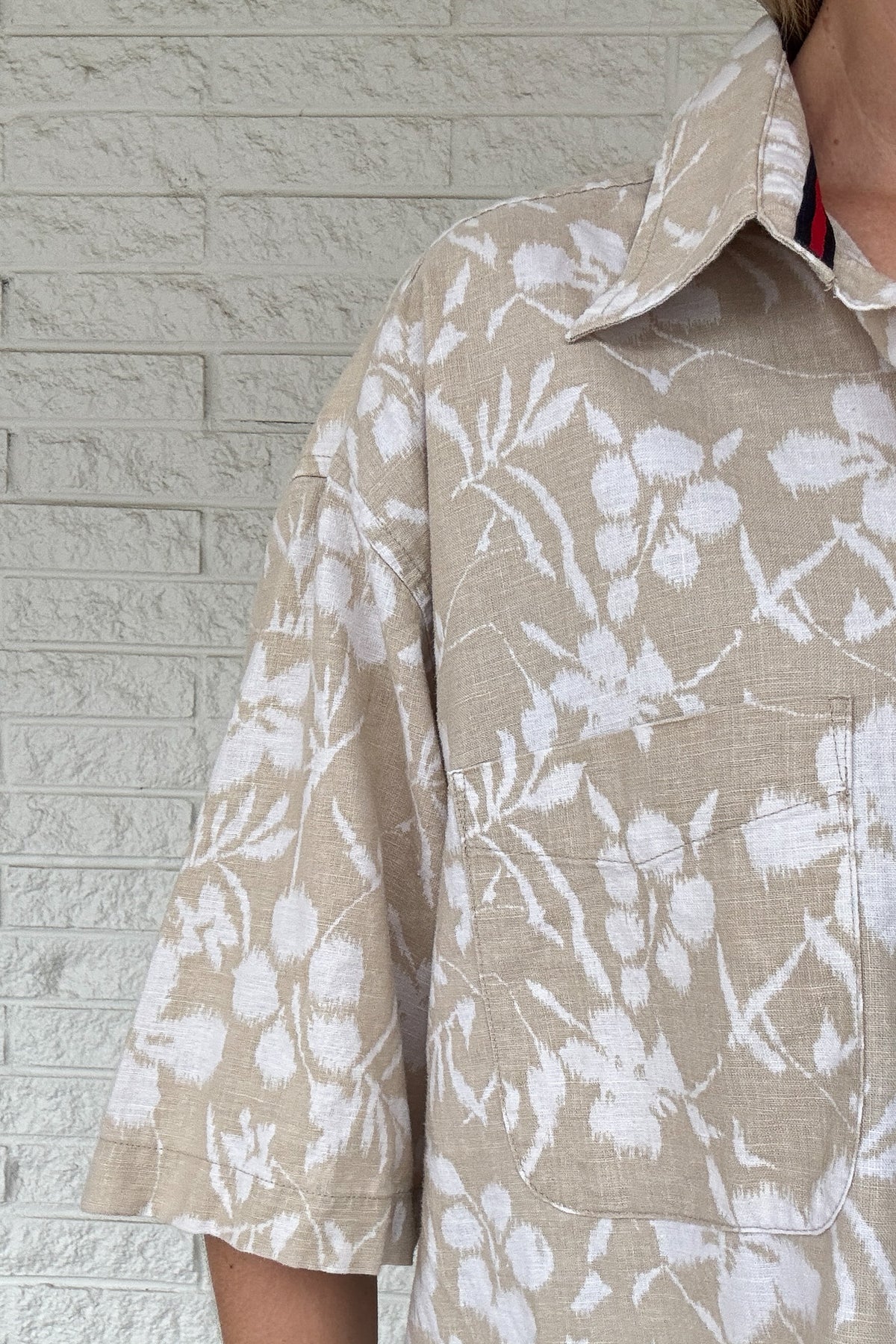 Front photo:
VonVie Harlow natural and white floral cropped button down shirt with relaxed elbow length sleeves

Back photo:
Back view of VonVie Harlow natural floral shirt with open back and red and navy ribbon ties