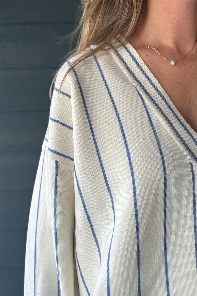 Close-up of FRNCH ivory striped cardigan sweater showing blue pinstripes, V-neckline and contrast ribbed trim.