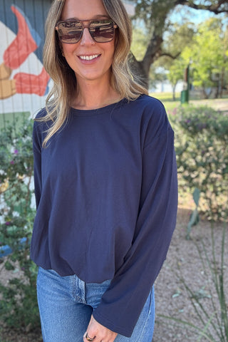 Women's navy blue long sleeve top with a relaxed fit, crew neckline, and drop shoulders. Styled with denim at Cotton & Cashmere Boutique.