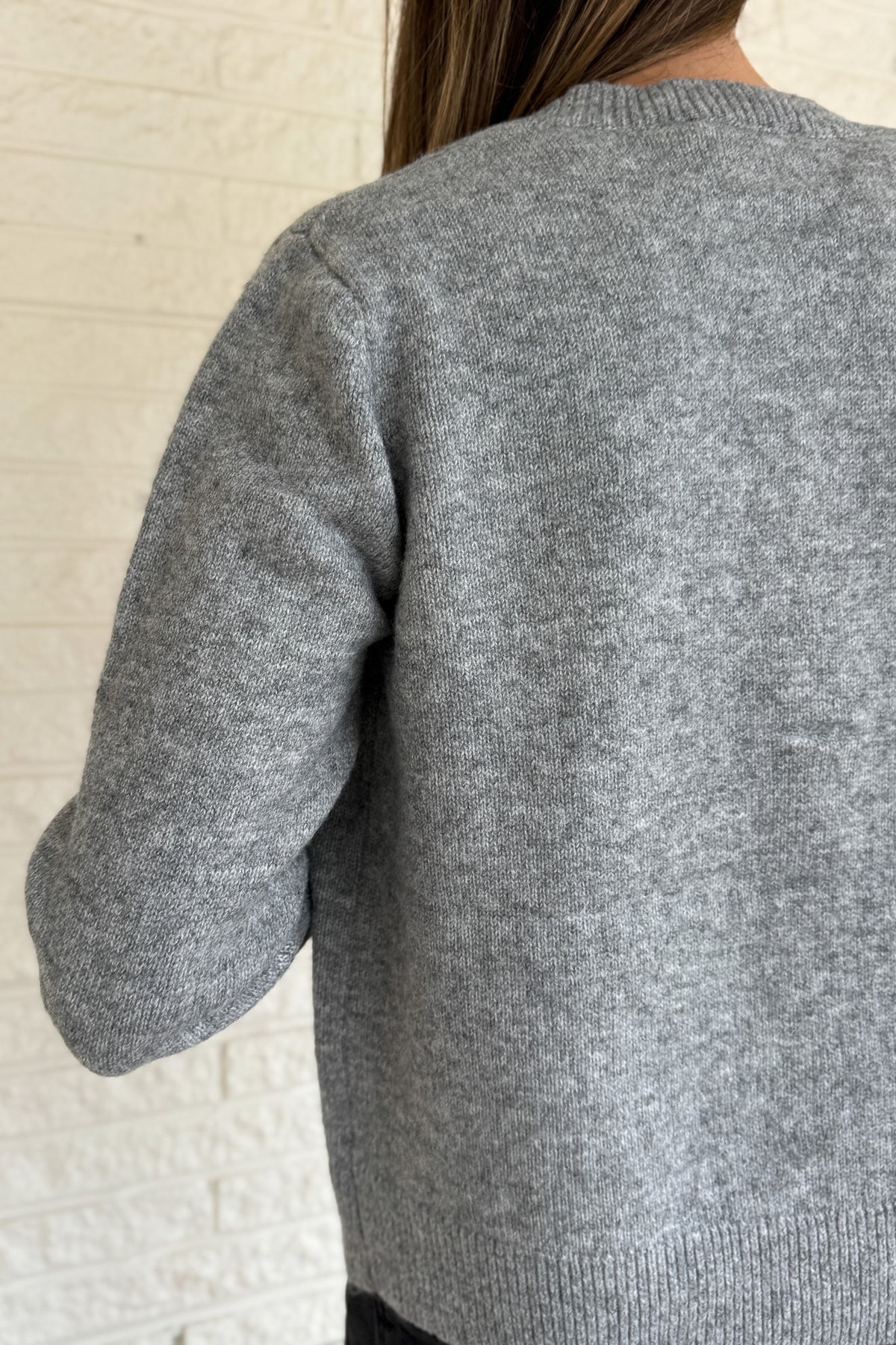 Designed in Spain, this soft grey cardigan brings a fun twist to a timeless classic. The colorful knit-covered buttons add a playful pop while keeping the look polished. It’s a cozy, easy-to-wear piece that pairs effortlessly with denim or trousers for everyday style.