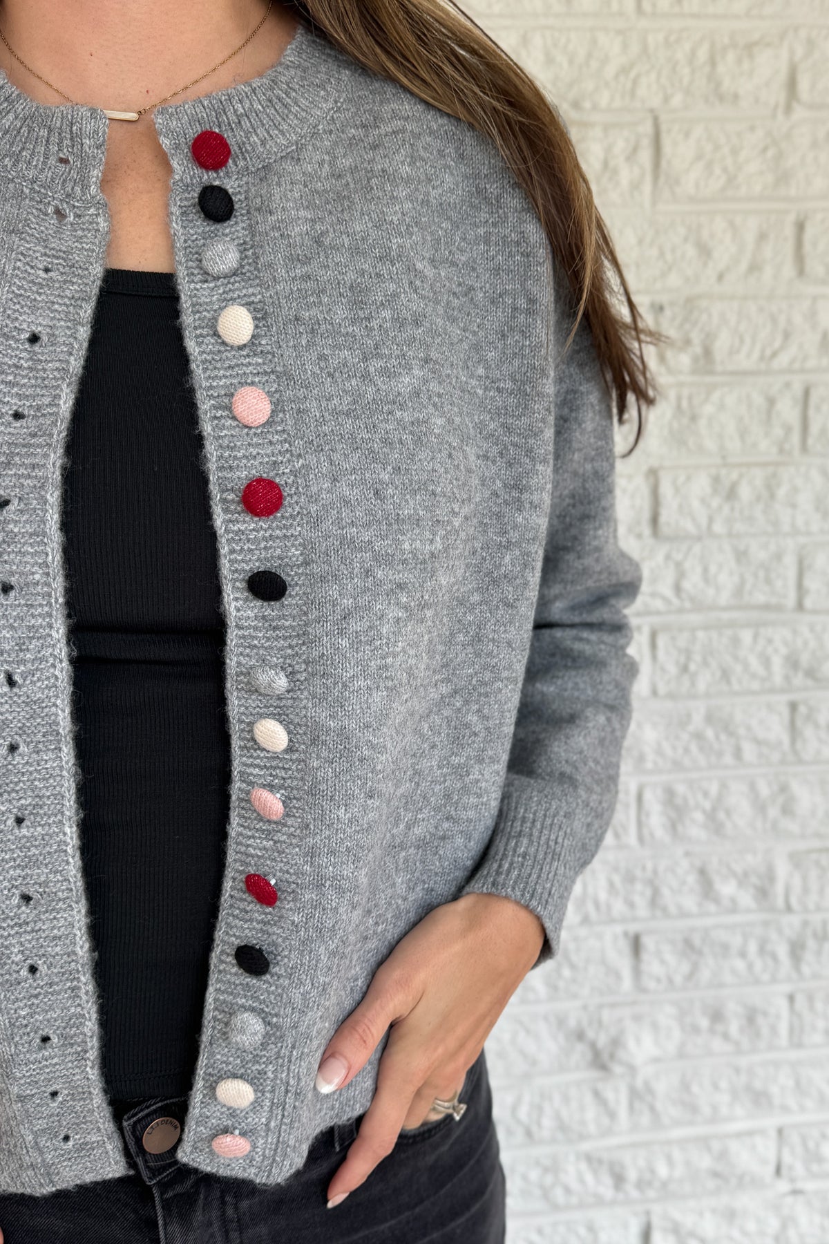 Designed in Spain, this soft grey cardigan brings a fun twist to a timeless classic. The colorful knit-covered buttons add a playful pop while keeping the look polished. It’s a cozy, easy-to-wear piece that pairs effortlessly with denim or trousers for everyday style.