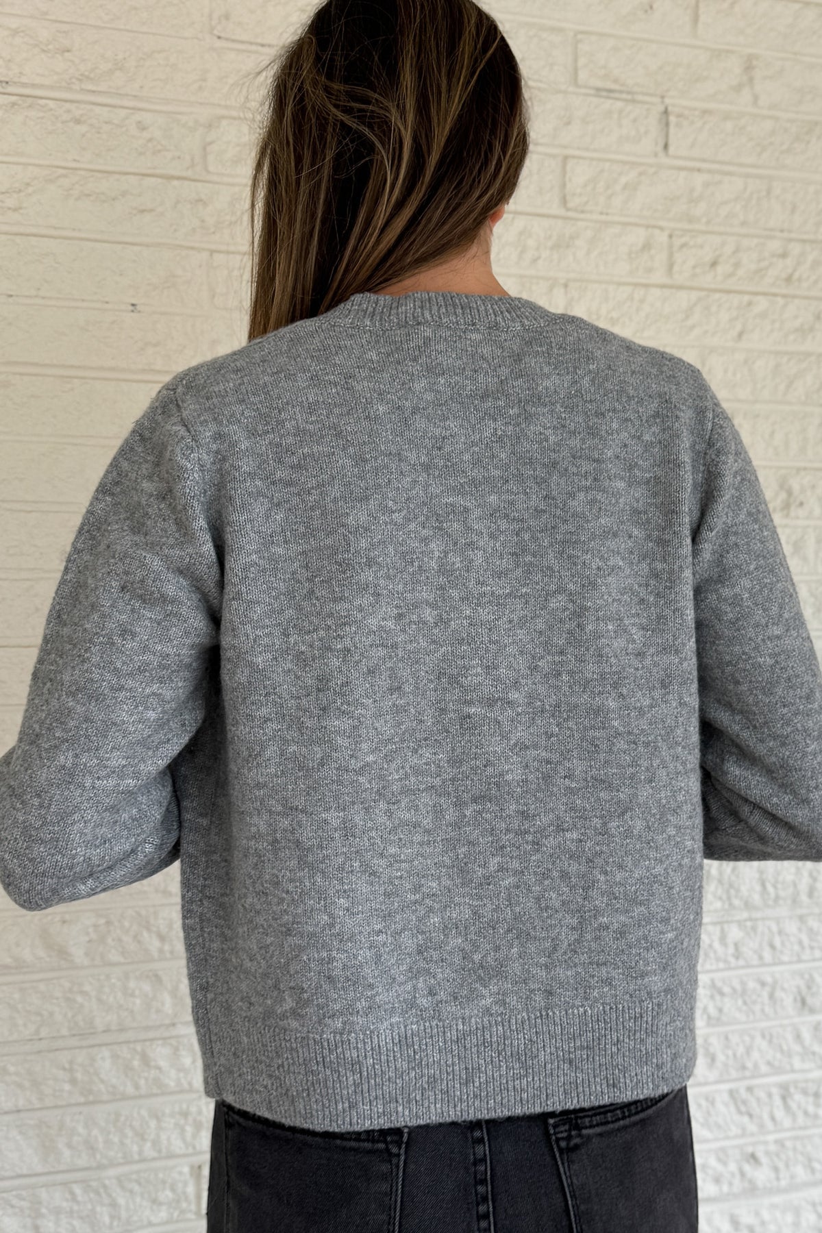 Designed in Spain, this soft grey cardigan brings a fun twist to a timeless classic. The colorful knit-covered buttons add a playful pop while keeping the look polished. It’s a cozy, easy-to-wear piece that pairs effortlessly with denim or trousers for everyday style.