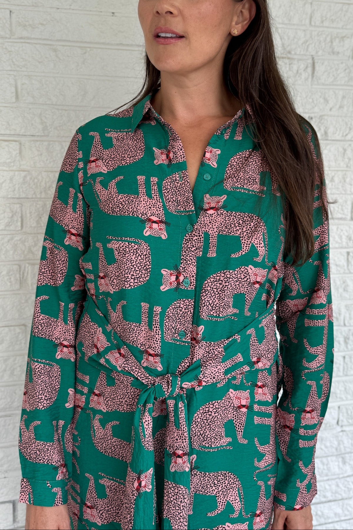 Designed in Spain, this playful shirt dress adds a touch of charm to your everyday wardrobe. Featuring a button-up front, classic collar, and an adjustable waist tie, it blends tailored structure with easy comfort. The bold green base and pink leopard print make it a fun, standout piece that’s perfect for workdays, weekends, or travel.