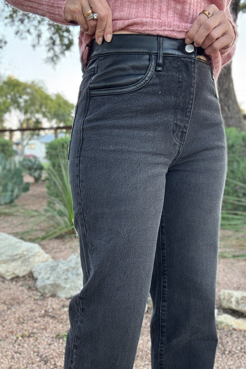 High-rise washed black denim jeans for women with a smooth black faux leather waistband, belt loops, and classic five-pocket styling.