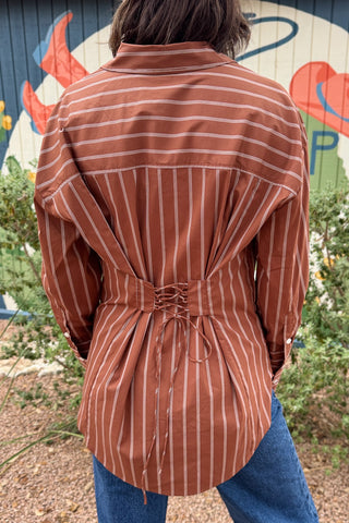 A rust striped button down top with an easy, relaxed fit and a unique lace up back detail. This women’s collared shirt features long sleeves, button cuffs, and an adjustable back that lets you create more shape at the waist. An effortless top to pair with jeans, trousers, or skirts for everyday wear.