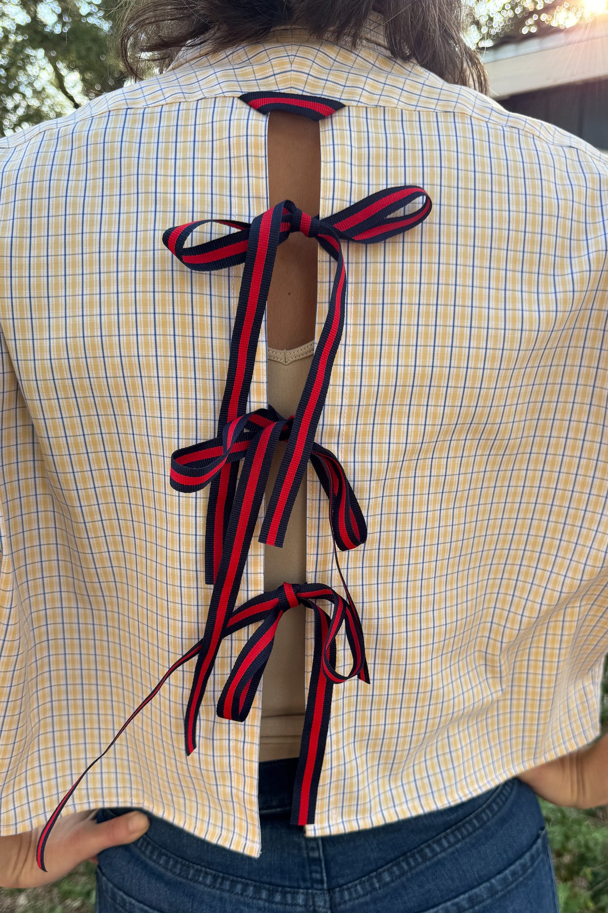 Back view of the VonVie Harlow upcycled plaid top with open-back styling and navy and red ribbon bows.
