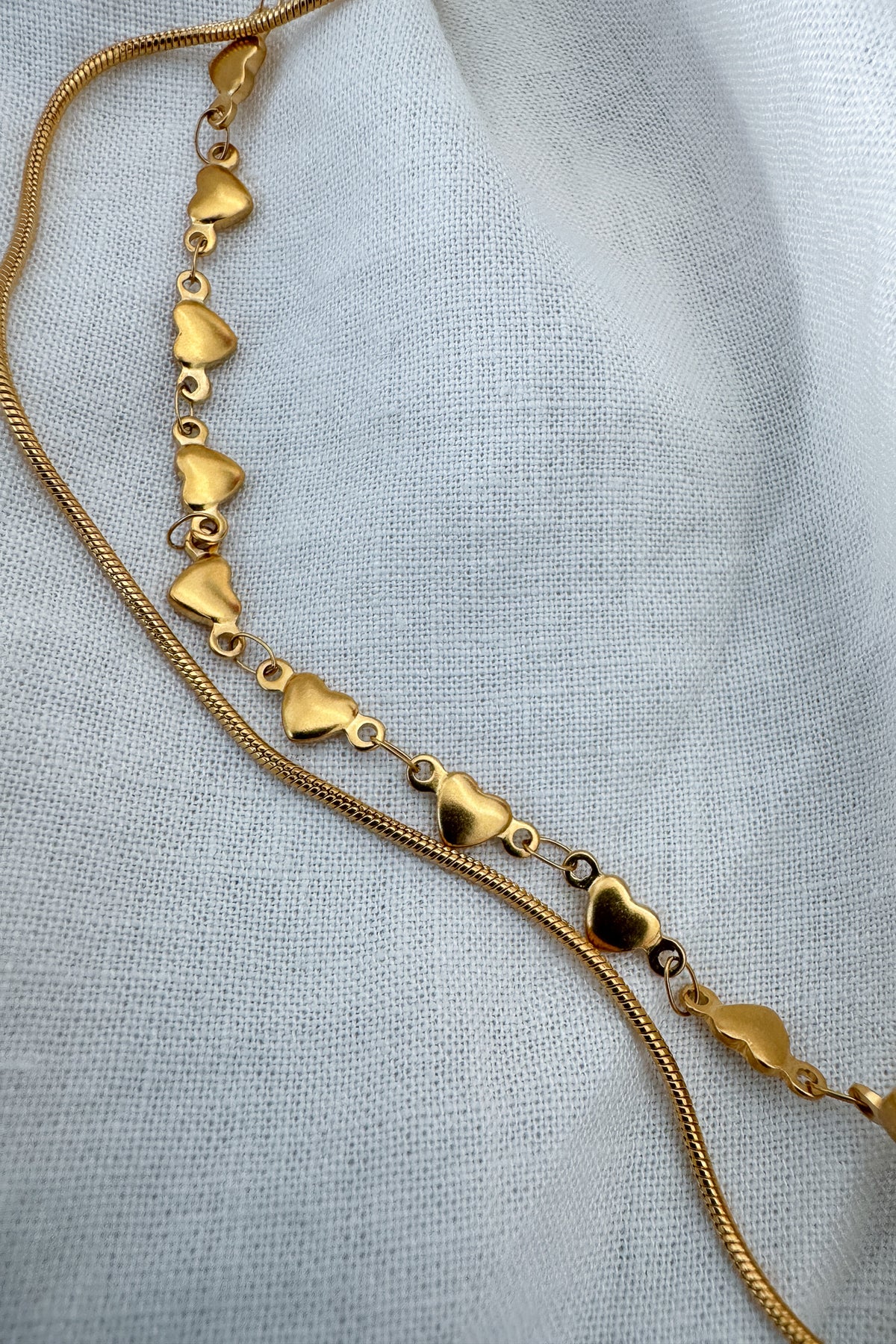 The string along necklace features a heart chain (hearts are solid on both sides), and a slim rope chain.

18k gold plated or stainless steel
water proof
double strand necklace
adjustable 14.5" - 16.5"
nickel / lead free
made with materials ethically sourced