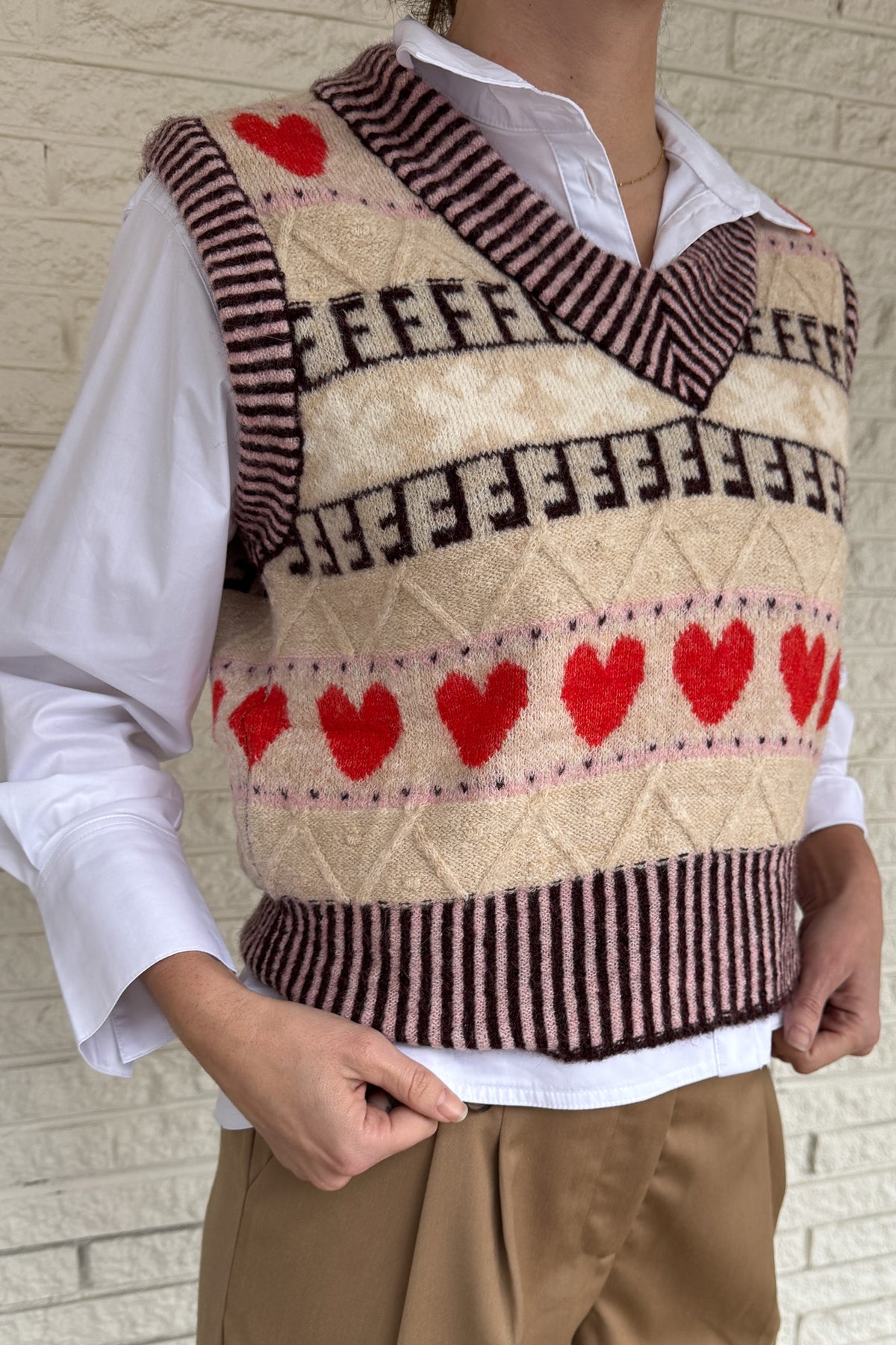 This sweater vest brings a charming, elevated touch to everyday outfits! Designed in France, it features a soft knit with a classic V neckline and a playful heart pattern that feels fun but still easy to wear. The neutral base makes it simple to style over a crisp button down or worn on its own as the seasons shift. It layers beautifully without adding bulk and gives your look a cozy, styled finish for workdays or casual plans. An easy piece to dress up denim or add interest to simple basics!