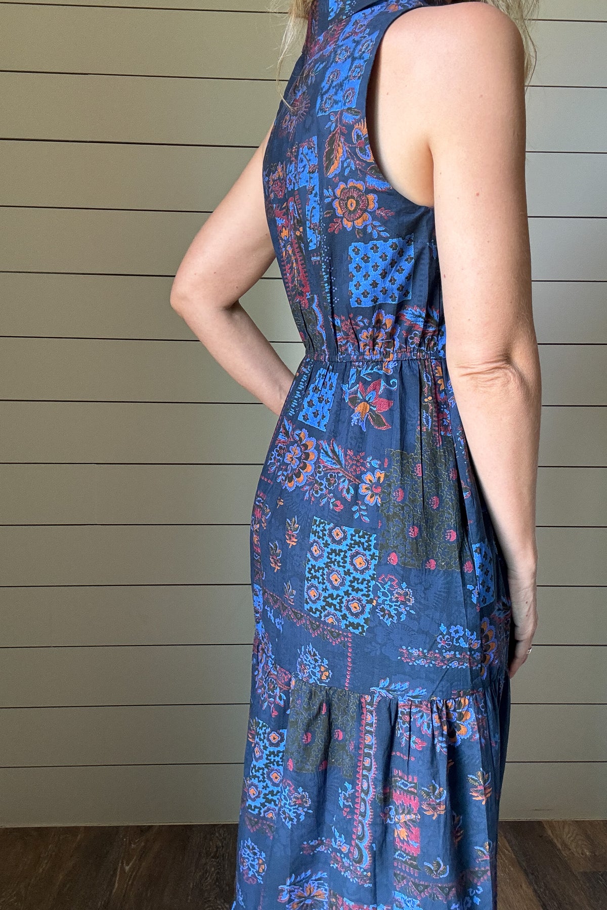 Say hello to the Indigo Garden Maxi Dress—an easy favorite for warm days. Made from 100% cotton, this sleeveless maxi is soft, breathable, and light. The button-front bodice and collared neckline give it a clean, polished shape, while the tiered skirt keeps the look relaxed. The printed fabric features a mix of floral and geometric designs in rich indigo, rust, and blue tones. It’s unlined, so it feels cool and comfortable, and yes—it has pockets. Dress it up or down, this one goes wherever your day takes y