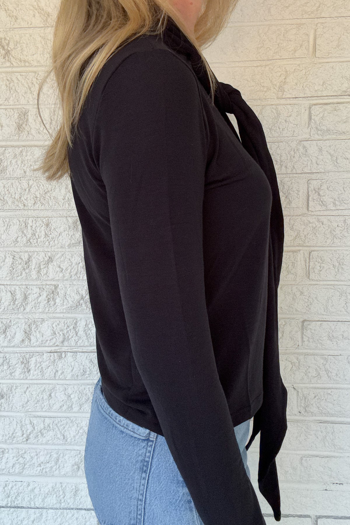 Designed in Spain, this black knit top brings an elegant touch to everyday dressing. The soft stretch fabric drapes beautifully, while the attached tie neckline adds a polished finish. Effortless yet refined, it’s the perfect piece to wear solo or layered under blazers, vests, or cardigans