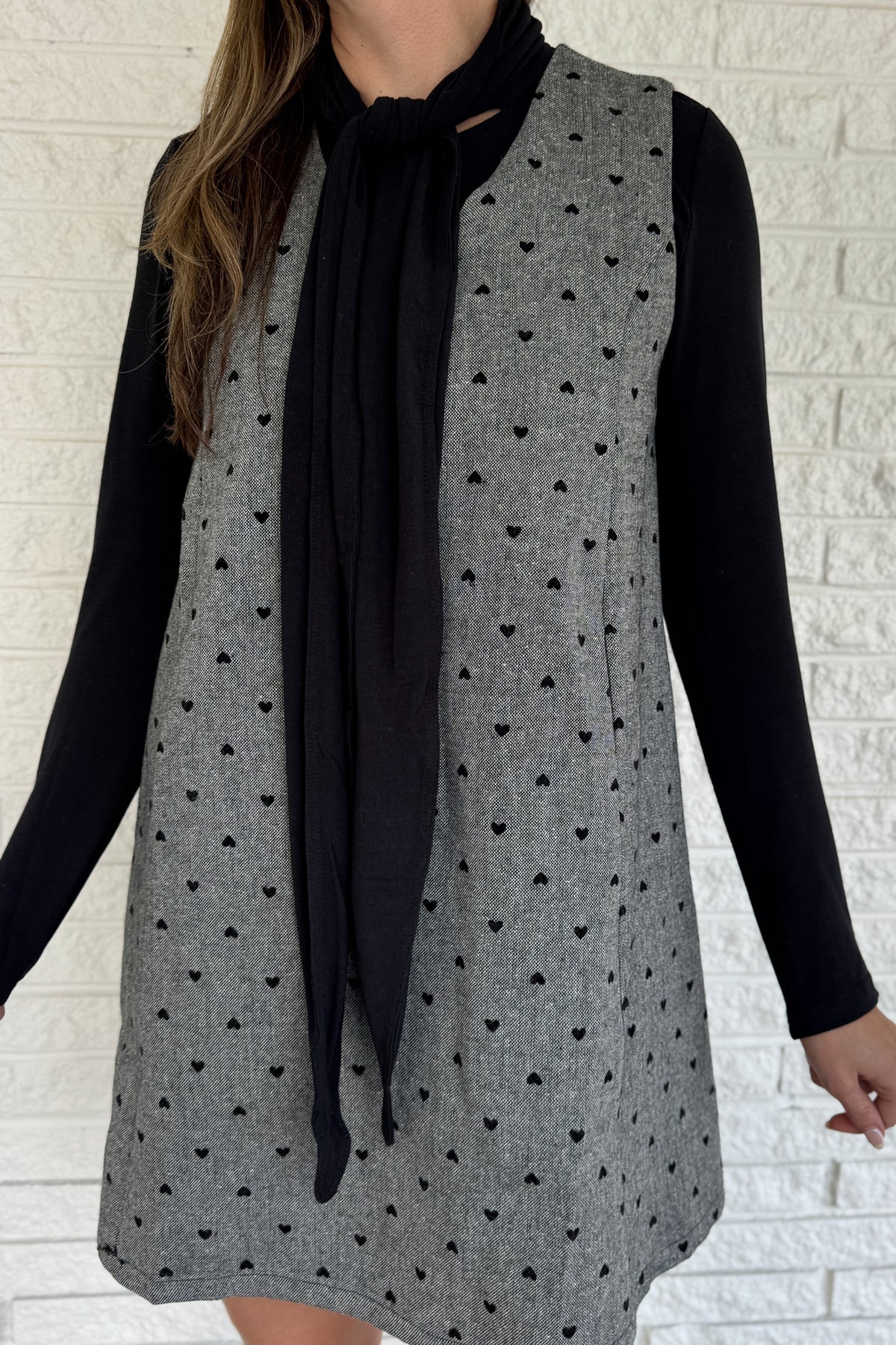 Designed in Spain, this black knit top brings an elegant touch to everyday dressing. The soft stretch fabric drapes beautifully, while the attached tie neckline adds a polished finish. Effortless yet refined, it’s the perfect piece to wear solo or layered under blazers, vests, or cardigans