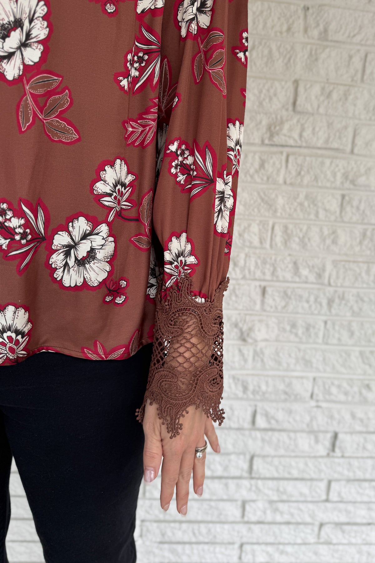 A floral blouse with a refined touch. Designed in a warm brown base with bold contrast blooms and lace-trimmed sleeves, this top adds an elevated feel to everyday dressing. Lightweight with subtle drape, it pairs easily with denim or trousers and works well for both weekday and weekend.