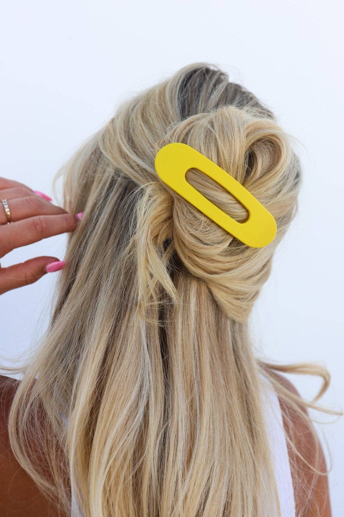 Yellow hair clip in a person's blonde hair on a white background