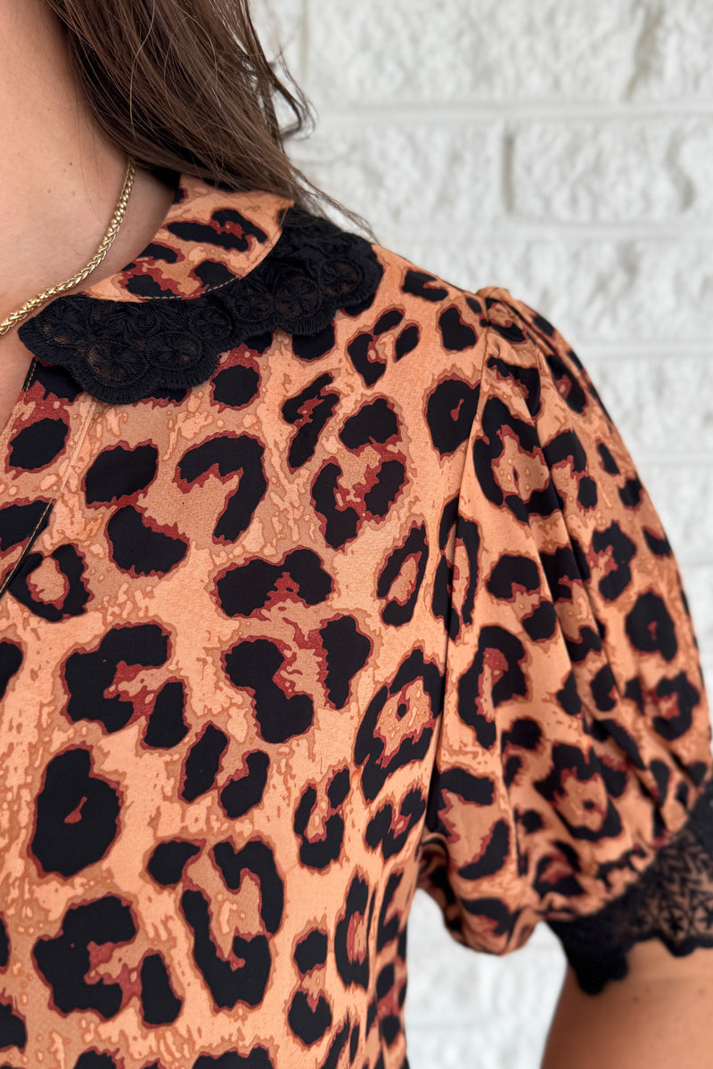 &nbsp;This leopard print blouse is bold and feminine with playful details. A black lace collar and matching lace trim on the puff sleeves give this classic print a chic update. Lightweight and easy to wear, it’s perfect for dressing up denim or pairing with tailored pants.
