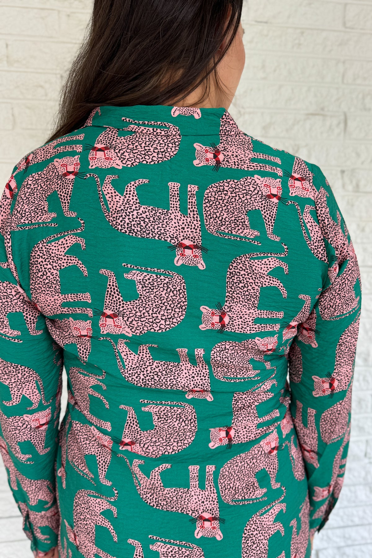 Designed in Spain, this playful shirt dress adds a touch of charm to your everyday wardrobe. Featuring a button-up front, classic collar, and an adjustable waist tie, it blends tailored structure with easy comfort. The bold green base and pink leopard print make it a fun, standout piece that’s perfect for workdays, weekends, or travel.