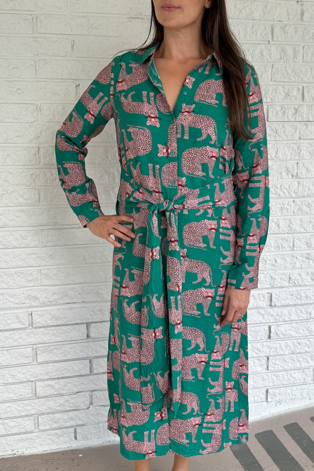 Designed in Spain, this playful shirt dress adds a touch of charm to your everyday wardrobe. Featuring a button-up front, classic collar, and an adjustable waist tie, it blends tailored structure with easy comfort. The bold green base and pink leopard print make it a fun, standout piece that’s perfect for workdays, weekends, or travel.