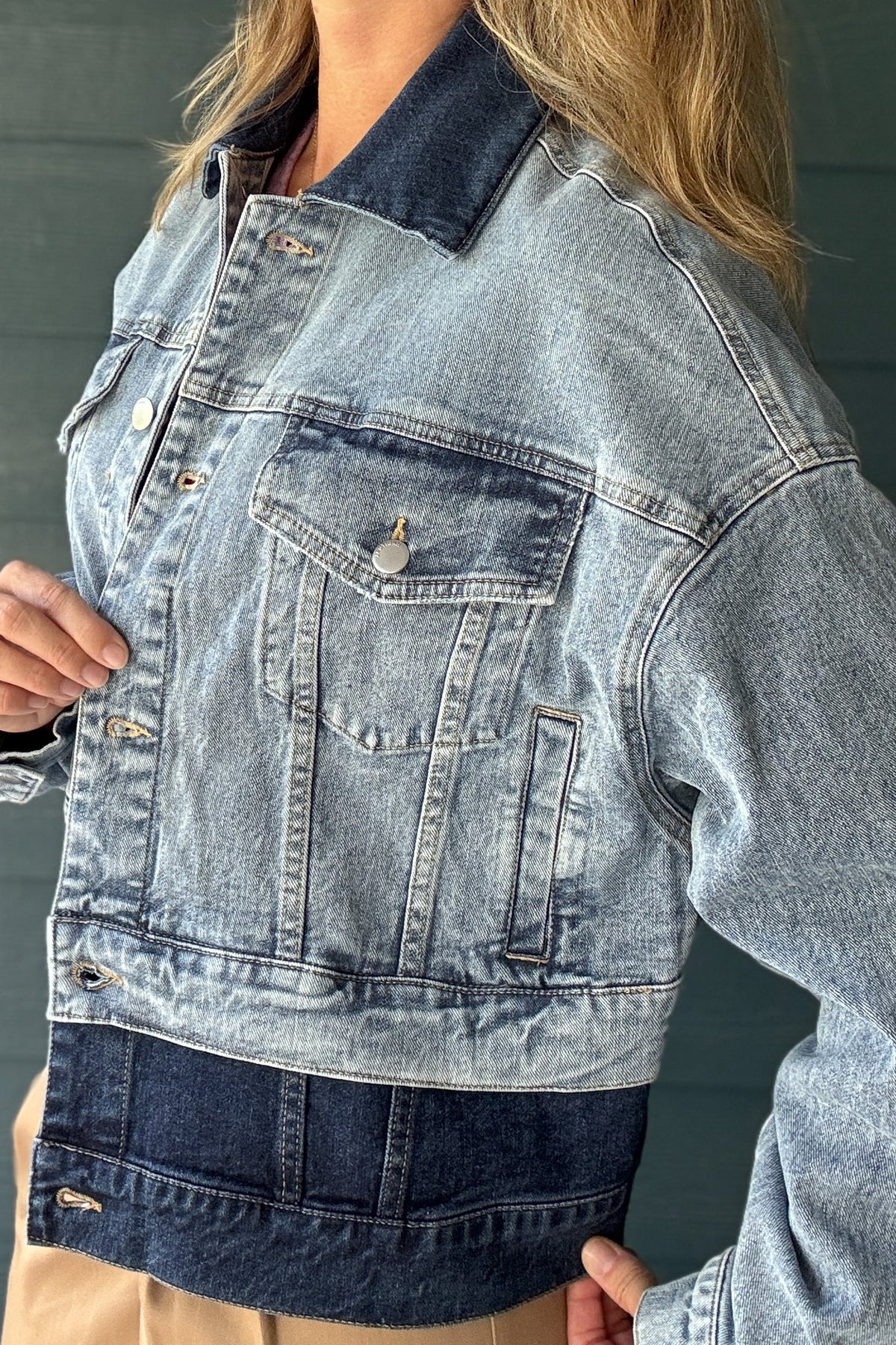 Detail view of women’s light and dark wash denim jacket with oversized sleeves, contrast collar and layered two-tone denim design.