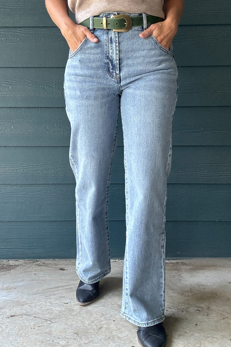 Front view of women’s light wash high-rise wide-leg jeans with a relaxed full-length silhouette and functional front pockets.