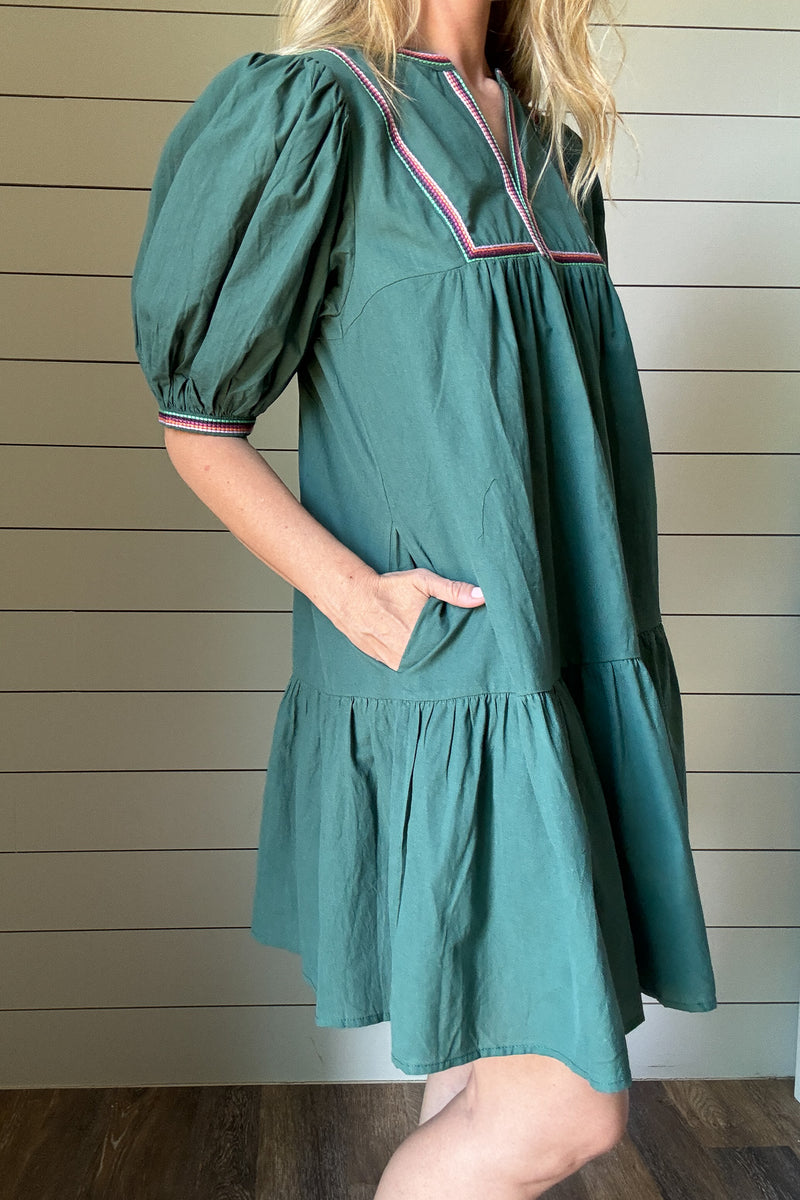 The Meadow Tiered Dress is a breezy, feminine style made for easy days. Crafted from 100% cotton, it’s soft, breathable, and perfect for warmer weather. This knee-length dress features three unlined tiers that create movement and a relaxed shape. The standout details are in the sleeves and neckline—billowed sleeves with a dramatic puff and delicate straight-line embroidery that adds a touch of texture and charm. The same embroidery traces the neckline for a finished, elevated look. Did we mention she has po