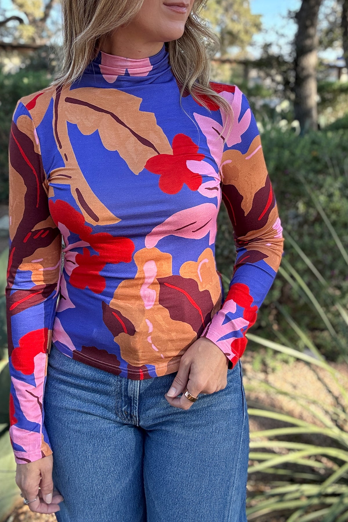 Women's long sleeve mock neck top with bold abstract floral print in blue, red, pink, and warm brown at Cotton & Cashmere Boutique.