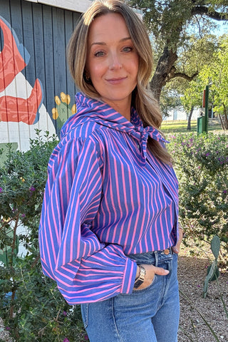 Women's blue and pink striped blouse with a matching tie-neck scarf, balloon sleeves, and button-front detail. Shop Cotton & Cashmere Boutique.