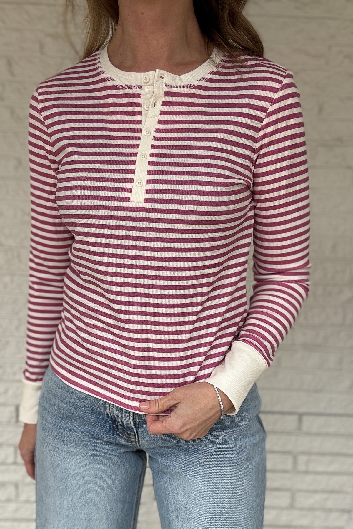 &nbsp; This fitted pink and cream striped henley top is an easy staple for everyday style. Designed with a soft stretch knit, it hugs the body without feeling tight and moves with you all day. The classic henley neckline adds a timeless touch, while the button front lets you adjust the look from casual to polished. Lightweight, it layers beautifully under jackets or stands on its own with denim. The pink and cream stripes keep it fresh and feminine, perfect for work, weekends, and everything in between.&nbs