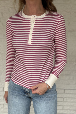 &nbsp; This fitted pink and cream striped henley top is an easy staple for everyday style. Designed with a soft stretch knit, it hugs the body without feeling tight and moves with you all day. The classic henley neckline adds a timeless touch, while the button front lets you adjust the look from casual to polished. Lightweight, it layers beautifully under jackets or stands on its own with denim. Women's fashion boutique Blanco Texas Johnson City Texas