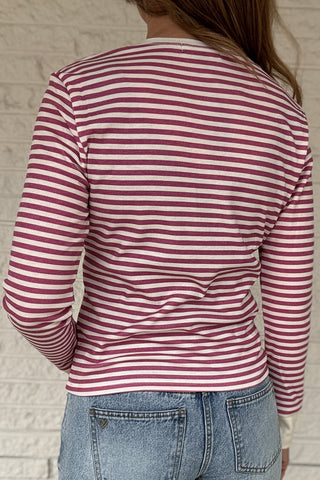 &nbsp; This fitted pink and cream striped henley top is an easy staple for everyday style. Designed with a soft stretch knit, it hugs the body without feeling tight and moves with you all day. The classic henley neckline adds a timeless touch, while the button front lets you adjust the look from casual to polished. Lightweight, it layers beautifully under jackets or stands on its own with denim. Women's fashion boutique Blanco Texas Johnson City Texas