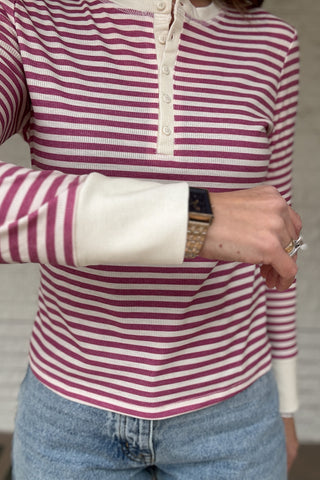 &nbsp; This fitted pink and cream striped henley top is an easy staple for everyday style. Designed with a soft stretch knit, it hugs the body without feeling tight and moves with you all day. The classic henley neckline adds a timeless touch, while the button front lets you adjust the look from casual to polished. Lightweight, it layers beautifully under jackets or stands on its own with denim. Women's fashion boutique Blanco Texas Johnson City Texas