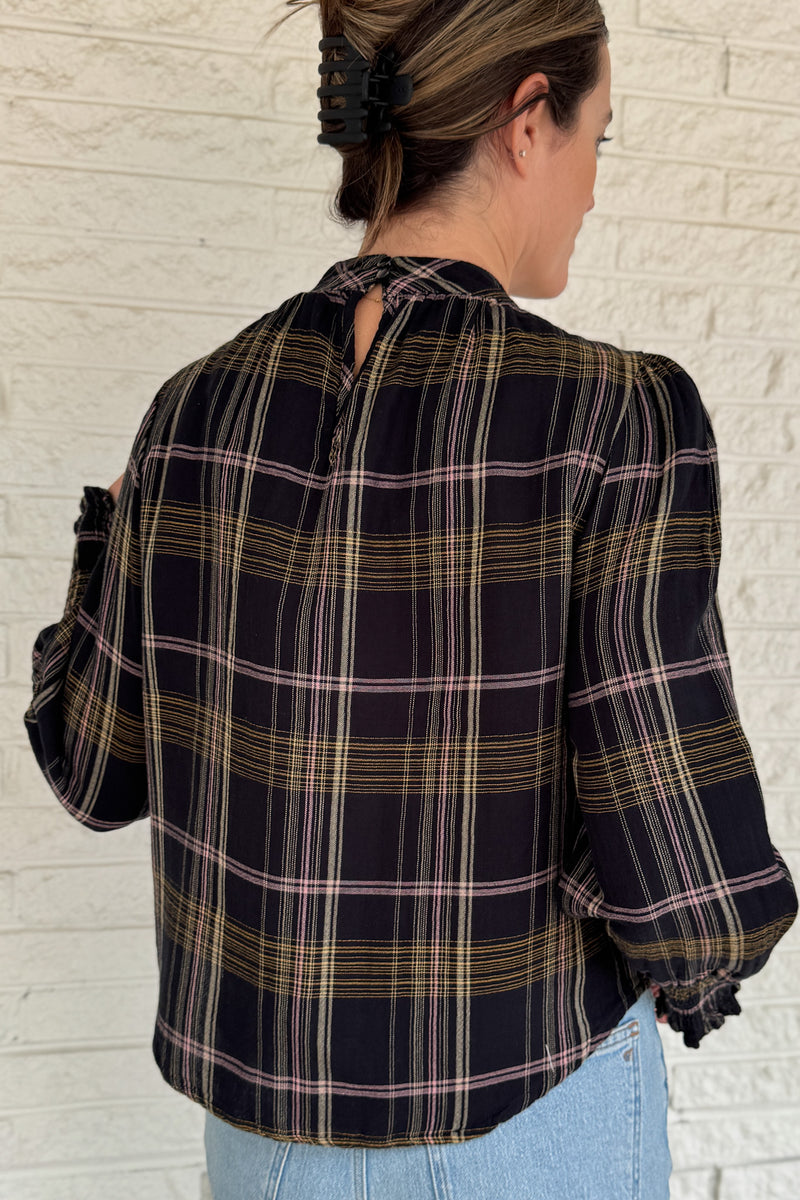 &nbsp;This plaid top blends classic style with feminine detail. Featuring a soft, lightweight drape, it buttons at the back of the neck for a clean finish. Smocked cuffs and subtle gathering at the neckline add texture and charm.