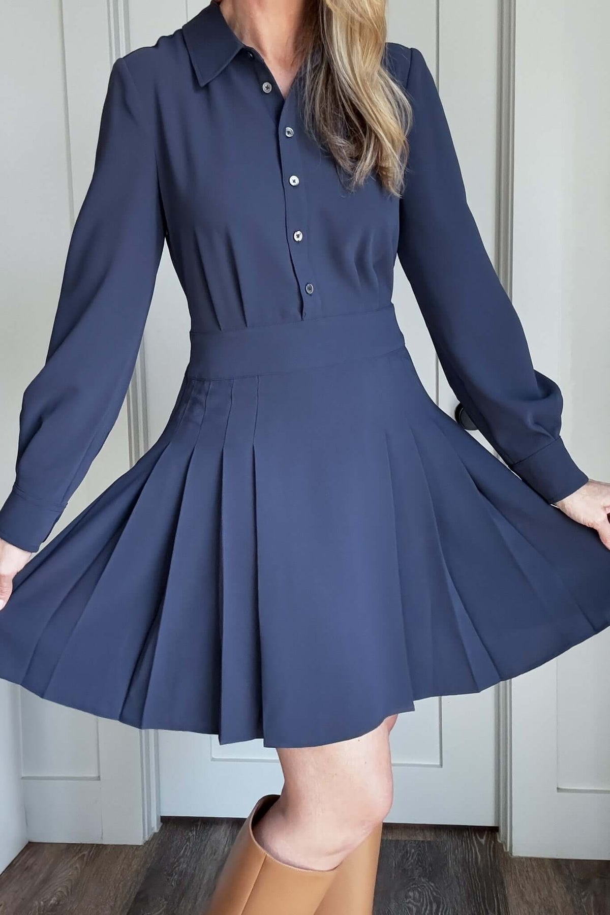 Elevate your style with our Pleated Skirt Dress! Featuring a button-up top and a pleated skirt that hits above the knee for a flattering look. The hidden zipper under the arm provides seamless wear, while the flowy and heavy weight fabric ensures comfort and eliminates the need for lining. Experience the perfect mix of function and fashion.