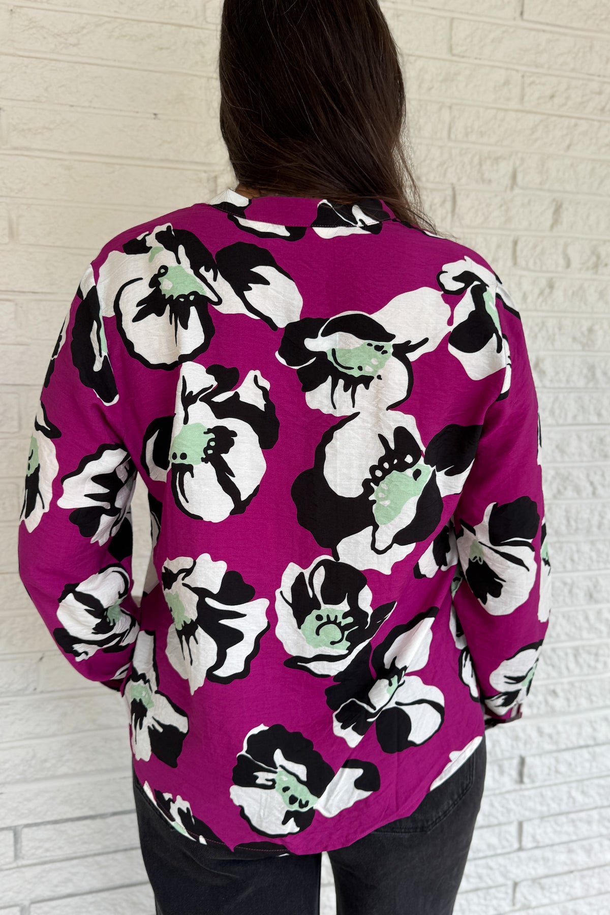 Designed in Spain, this bold floral blouse makes a statement with its vibrant magenta base and oversized poppy print. The lightweight viscose blend drapes beautifully, giving it a relaxed yet refined look. Perfect for pairing with black denim or trousers, it’s an easy way to add color and personality to your everyday style.