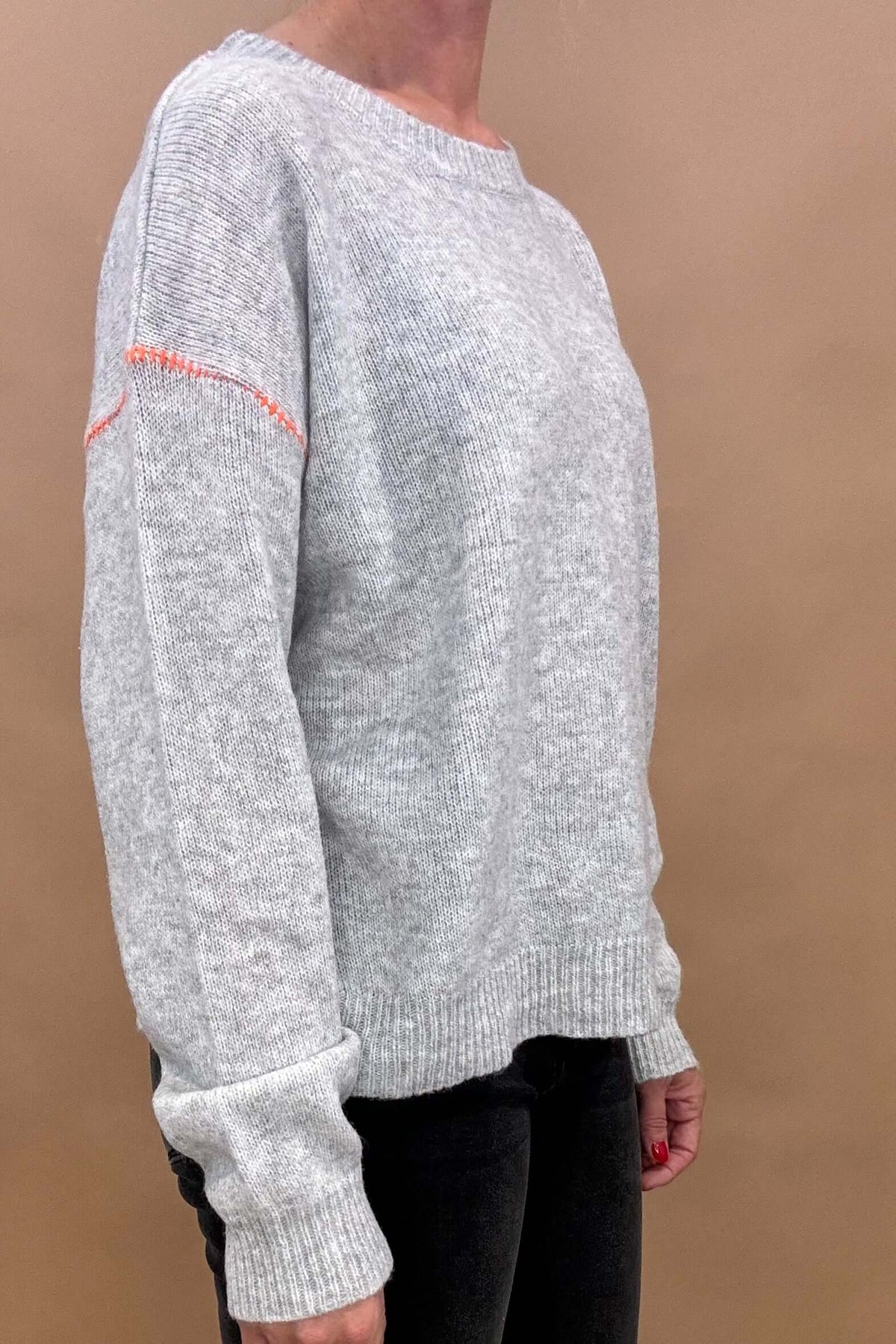 This Pop of Orange Sweater will make a chic statement this season. Its soft gray hue and exquisite orange stitching create a cozy yet refined look perfect for any occasion. The slightly oversized silhouette adds effortless elegance to your wardrobe.