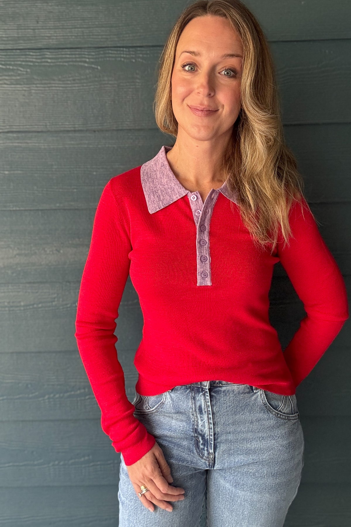 Close-up of women’s red knit polo sweater with lavender contrast collar, button placket and fitted long sleeves from Cotton & Cashmere boutique.
