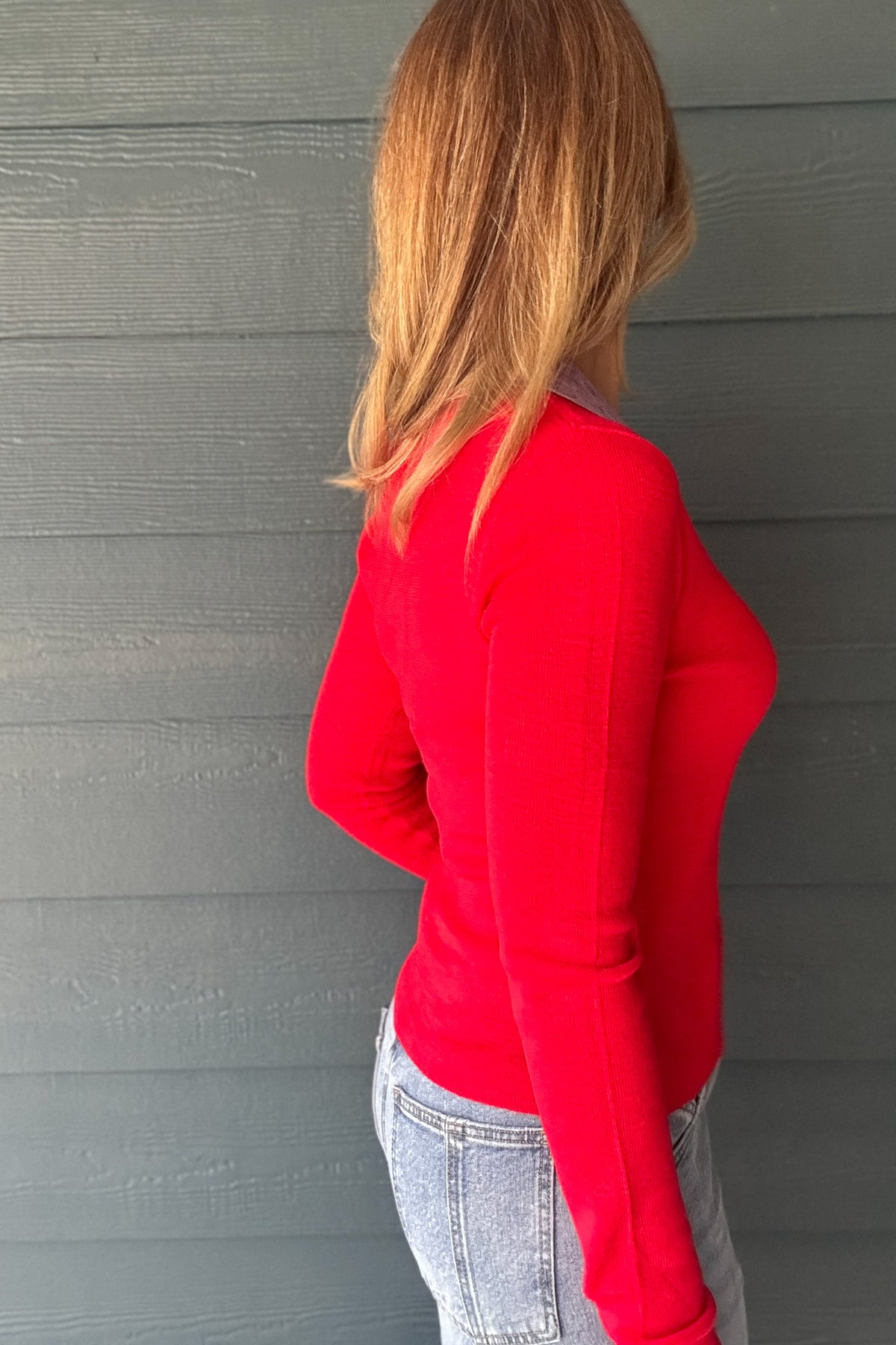 Women’s red knit polo top with lavender collar, button neckline and long sleeves styled with light wash denim