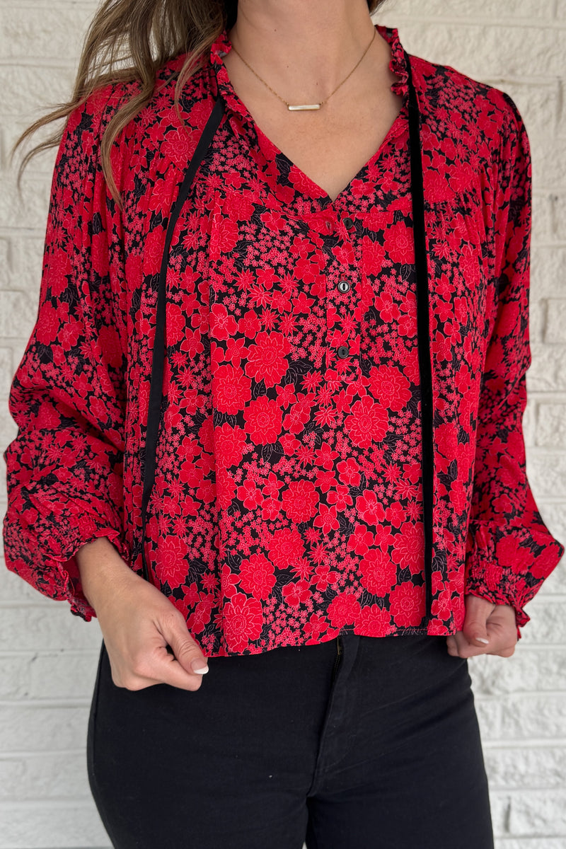 Bold and effortless, this floral top brings vibrant energy with zero fuss. The relaxed shape balances the statement print, and the soft velvet trim adds a touch of sophistication. Lightly gathered cuffs finish the look with subtle volume. Easy to style for day or dinner.