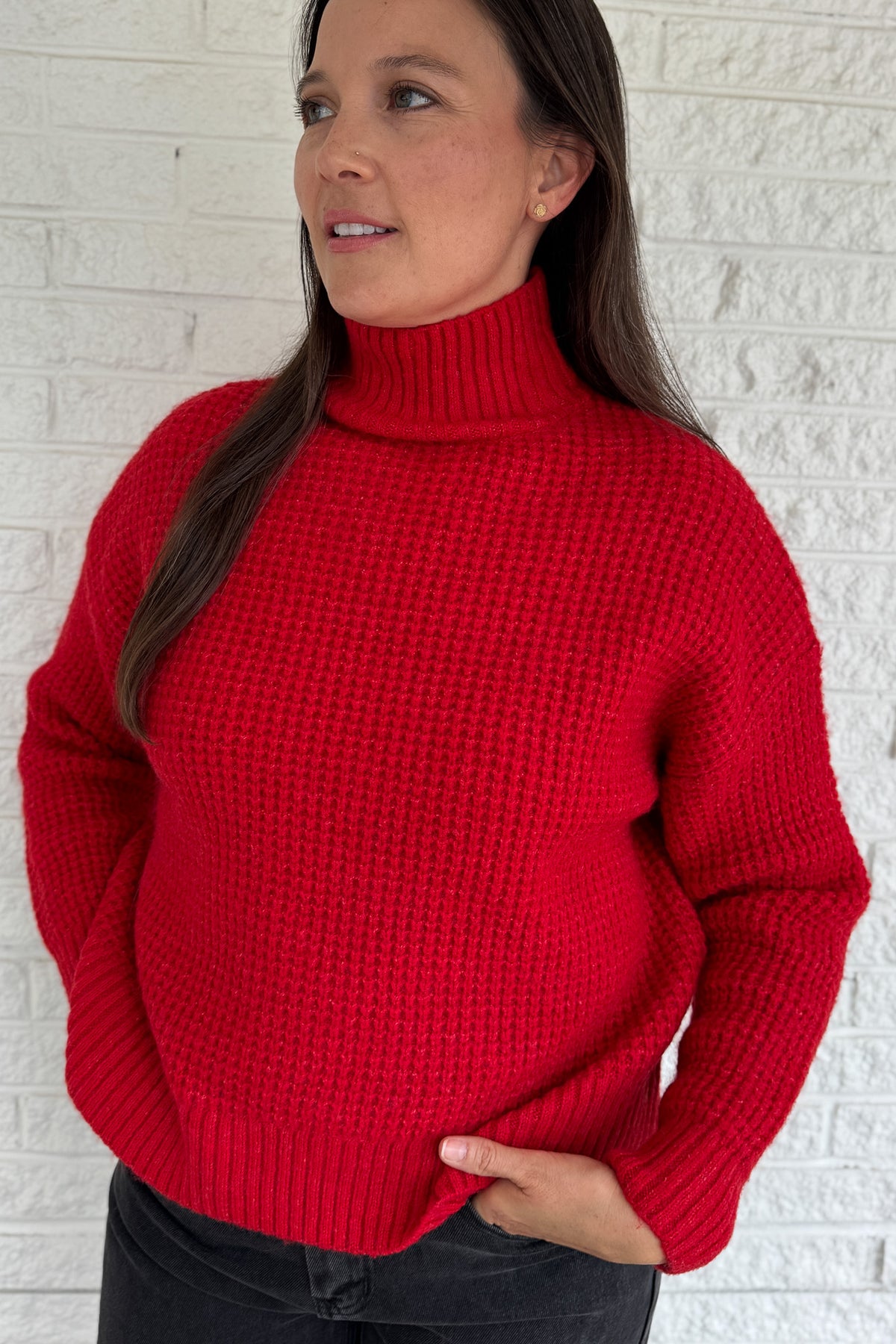 This bold red oversized sweater brings warmth and style together in one easy piece. Knitted in a soft, textured “square” weave, it features a cozy stand-up collar and ribbed finishes that keep the look clean and structured. Perfect for pairing with denim or a skirt for effortless everyday wear.