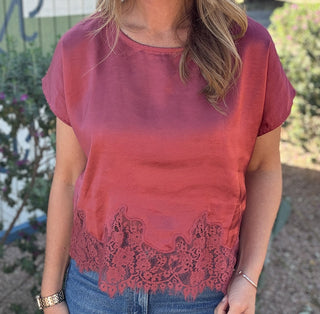 Women's dusty rose satin blouse with short sleeves, a relaxed fit, and delicate floral lace trim along the hem. Shop Cotton & Cashmere Boutique.