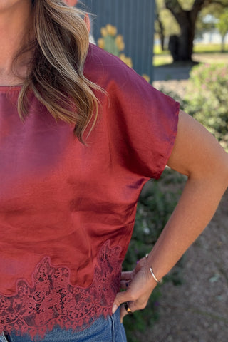 Feminine rose pink satin top featuring a soft sheen, round neckline, relaxed short sleeves, and intricate scalloped lace hem.