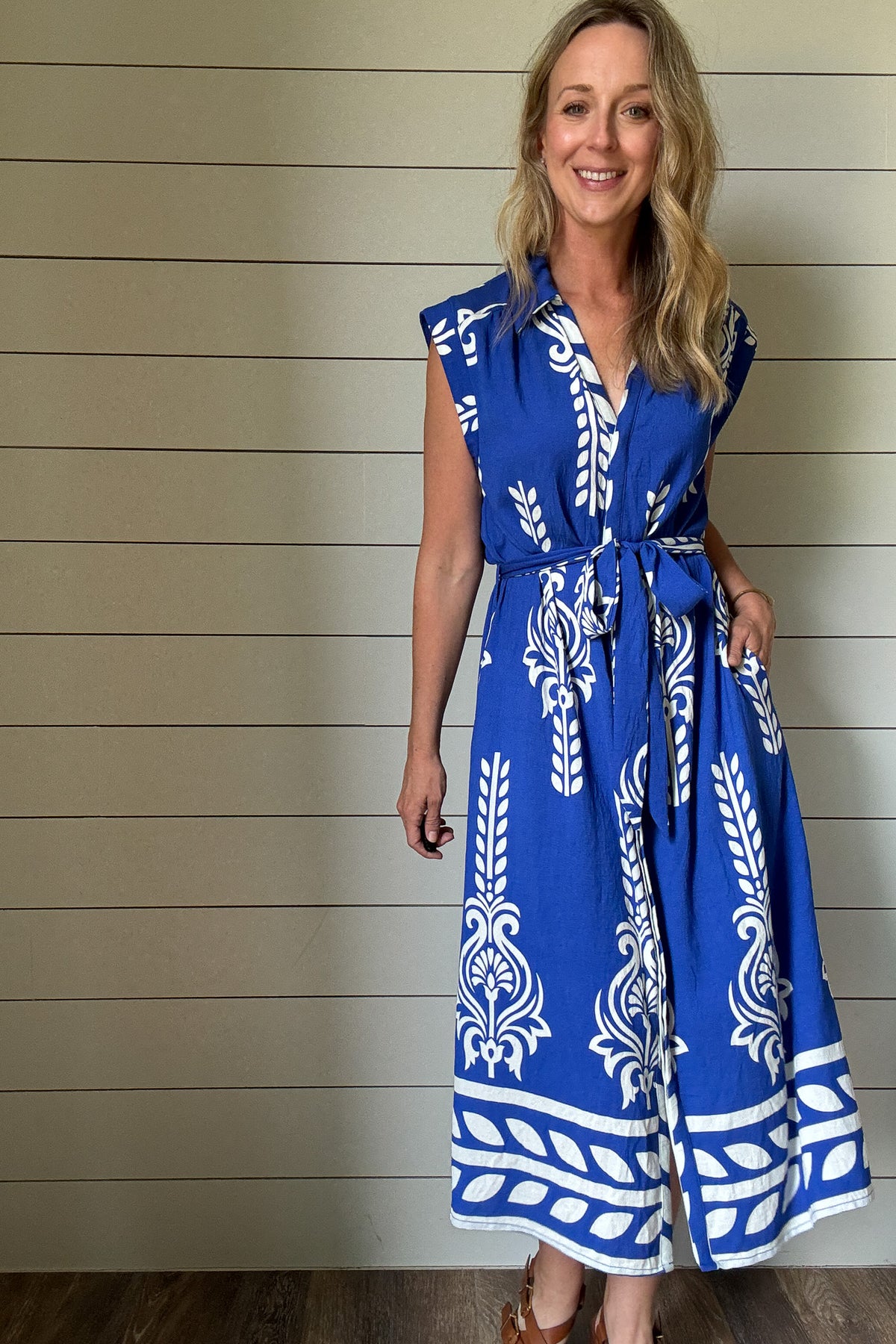 This striking blue and white midi dress brings effortless vacation vibes to your everyday. Designed with a flattering button-front and soft cap sleeves, the standout print and subtle structure make it an easy favorite. The fabric-covered buttons add a polished touch, while the adjustable tie belt defines the waist without feeling fussy. Made from rayon blend, it's unlined but not sheer—light enough for warm days with full coverage you can count on. Bold in detail and easy to wear, it’s perfect for brunch, b