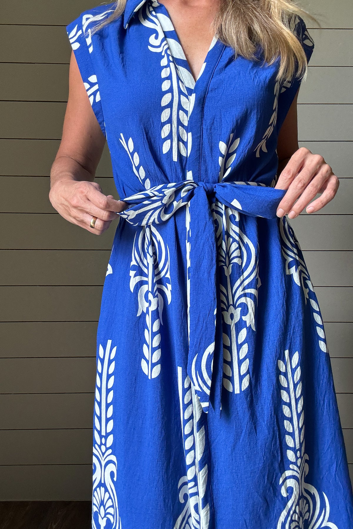 This striking blue and white midi dress brings effortless vacation vibes to your everyday. Designed with a flattering button-front and soft cap sleeves, the standout print and subtle structure make it an easy favorite. The fabric-covered buttons add a polished touch, while the adjustable tie belt defines the waist without feeling fussy. Made from rayon blend, it's unlined but not sheer—light enough for warm days with full coverage you can count on. Bold in detail and easy to wear, it’s perfect for brunch, b