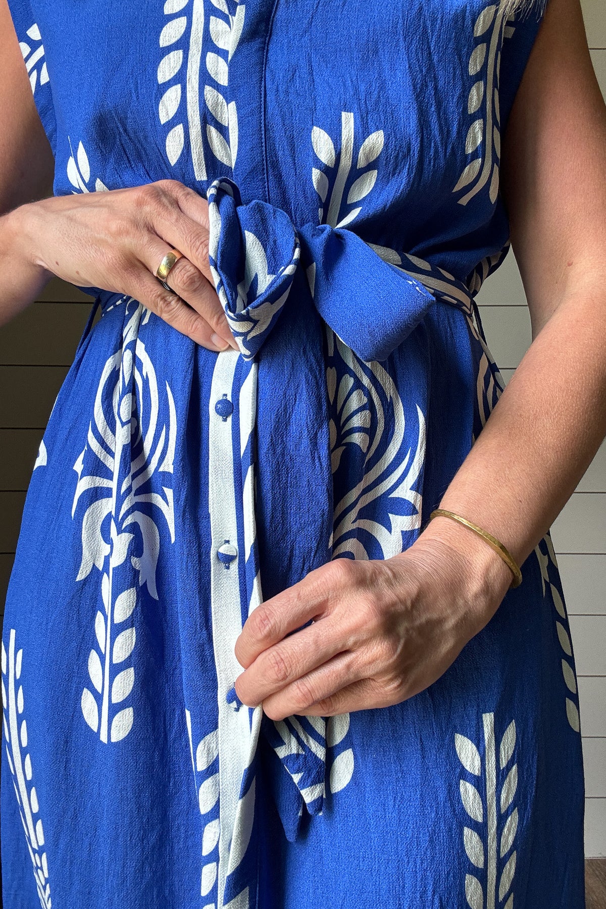 This striking blue and white midi dress brings effortless vacation vibes to your everyday. Designed with a flattering button-front and soft cap sleeves, the standout print and subtle structure make it an easy favorite. The fabric-covered buttons add a polished touch, while the adjustable tie belt defines the waist without feeling fussy. Made from rayon blend, it's unlined but not sheer—light enough for warm days with full coverage you can count on. Bold in detail and easy to wear, it’s perfect for brunch, b