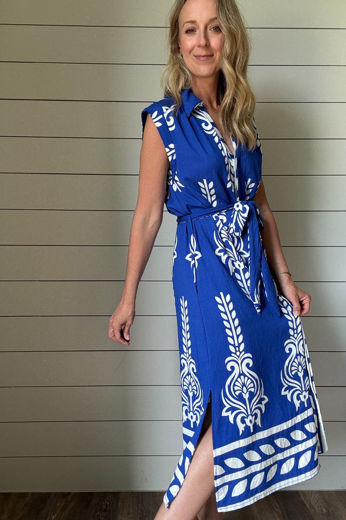 This striking blue and white midi dress brings effortless vacation vibes to your everyday. Designed with a flattering button-front and soft cap sleeves, the standout print and subtle structure make it an easy favorite. The fabric-covered buttons add a polished touch, while the adjustable tie belt defines the waist without feeling fussy. Made from rayon blend, it's unlined but not sheer—light enough for warm days with full coverage you can count on. Bold in detail and easy to wear, it’s perfect for brunch, b