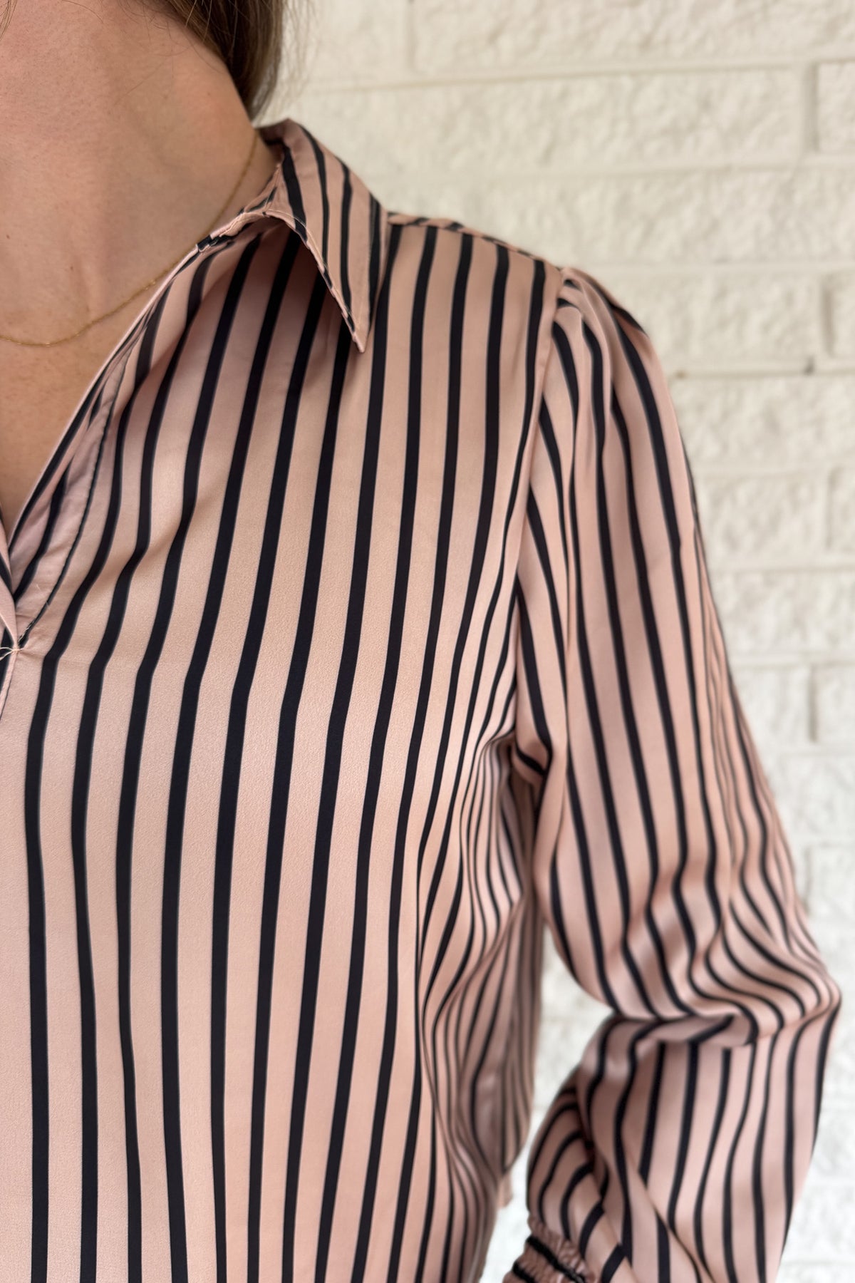 Soft satin with a polished drape, this striped top feels elevated yet easy. The relaxed silhouette and split neckline make it simple to style, while the vertical stripes elongate your frame. Smocked cuffs add a feminine finishing touch. Dress it up for work or keep it casual with denim.