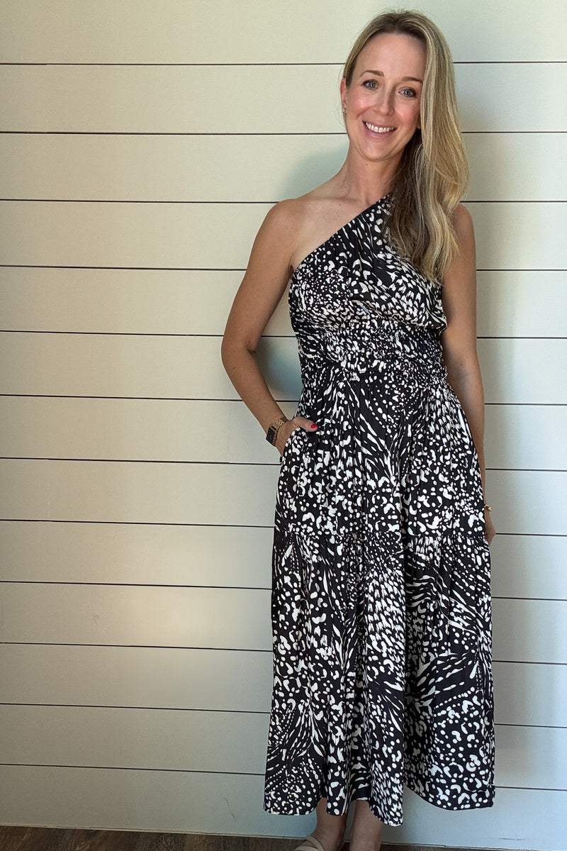 &nbsp;Make a statement with this sleek and modern one-shoulder dress. The satin fabric gives it just the right amount of sheen, while the black and white abstract print adds a bold twist. It’s unlined and lightweight—perfect for summer nights or dressing up your everyday. The smocked waist keeps things flattering, and yes—it has pockets. Wear it with slides or a strappy heel and you're good to go.