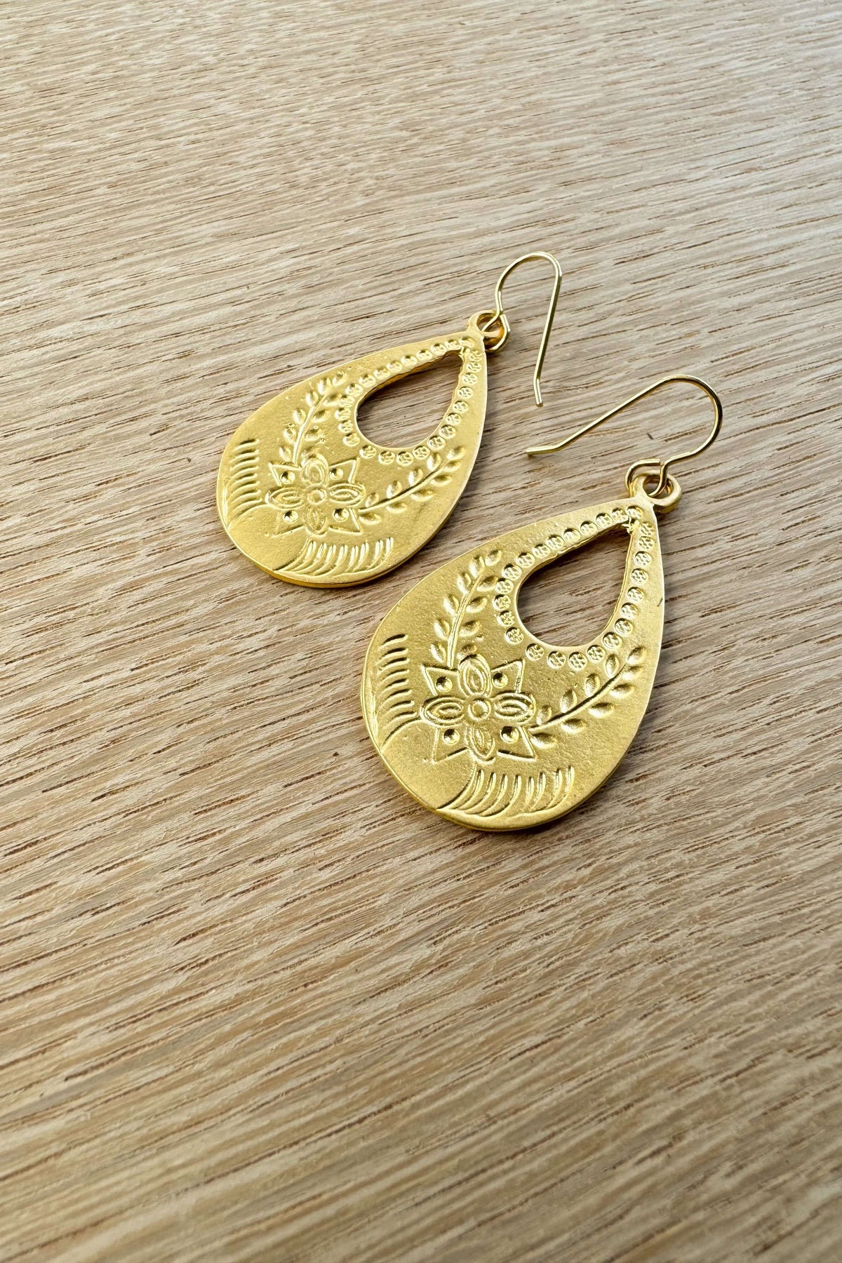 Matte gold vintaged styled flower stamped teardrop hoop earrings on 10k gold plated ear wires. They hang approximately 2 1/8 inches.

Hand made in the USA