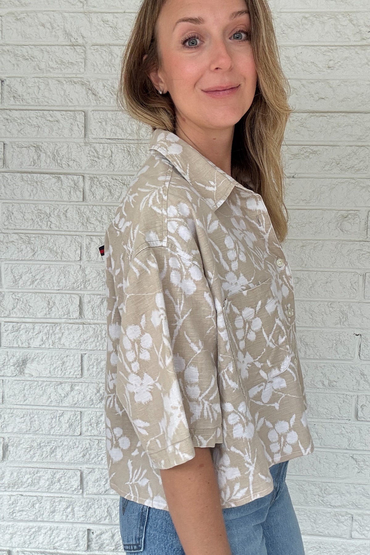 Front photo:
VonVie Harlow natural and white floral cropped button down shirt with relaxed elbow length sleeves

Back photo:
Back view of VonVie Harlow natural floral shirt with open back and red and navy ribbon ties
