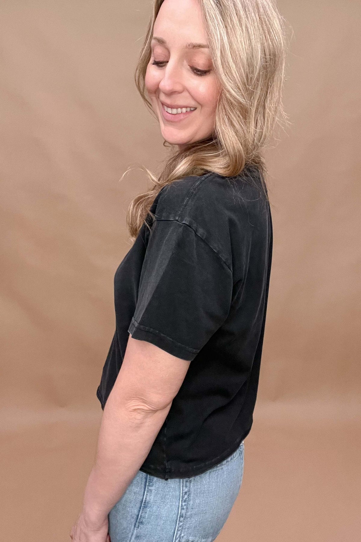 This black mineral washed tee features a slight crop and a raw bottom hem, creating an effortless look that hits at the top of the hips. Perfectly paired with denim for a stylish and comfortable outfit.